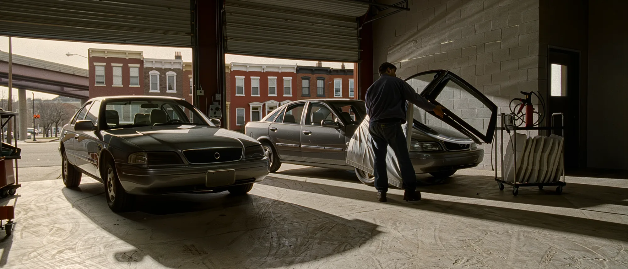 A glass technician lifting a new laminated windshield out of a padded rack in the Auto Glass Installed bay off East Columbia Avenue in Fishtown